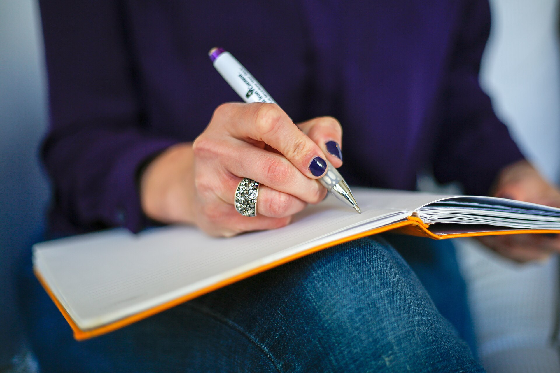 Hand schreibt mit Stift in ein Notizbuch – Kündigungsvorlagen zum Ausfüllen